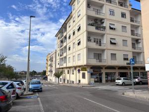 a tall white building with cars parked in a parking lot at Come a Casa Tua in Sassari