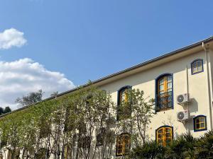 a large white building with trees in front of it at Pousada Vale do Queijo Serro in Sêrro