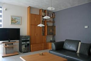 ein Wohnzimmer mit einem schwarzen Ledersofa und einem TV in der Unterkunft Bed & Breakfast VanAgt in Vlijmen