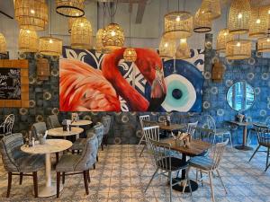 a restaurant with tables and chairs and a large painting of a bird at Sleek Modern 3BR Flat in Nunhead in London