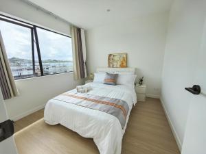 um quarto com uma cama grande e uma janela grande em Orewa New house with view on deck near Cafe,bush & river em Orewa