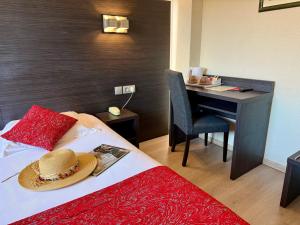 een hotelkamer met een bed met een hoed op een bureau bij Le Cheval Blanc in Arles