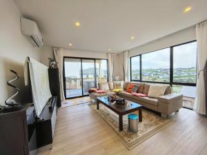 uma sala de estar com um sofá e uma mesa em Orewa New house with view on deck near Cafe,bush & river em Orewa