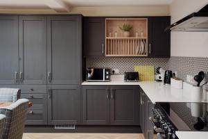 eine Küche mit schwarzen Schränken und weißen Arbeitsplatten in der Unterkunft Lime Kiln Cottage in Bridlington