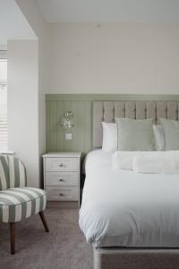 ein Schlafzimmer mit einem weißen Bett und einem Stuhl in der Unterkunft Lime Kiln Cottage in Bridlington