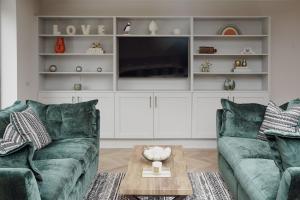 ein Wohnzimmer mit zwei grünen Sofas und einem Fernseher in der Unterkunft Lime Kiln Cottage in Bridlington + 25 Fotos