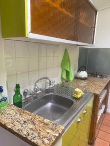 a kitchen sink with a green bottle on the counter at Dancers' Cottages in Cape Town +37 photos