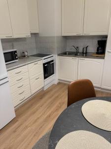 a kitchen with white cabinets and a table with chairs at Arctic Jaakko Suite in Rovaniemi +10 photos