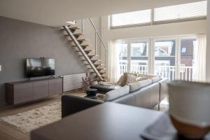 a living room with a couch and a tv at Sir William, duplex appartement Knokke in Knokke-Heist