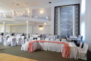 um salão de banquetes com mesas e cadeiras brancas e um grande ecrã em Ioannou Resort em Ptolemaida