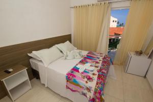 1 dormitorio con cama blanca y ventana en Pousada Verdes Mares, en Maragogi