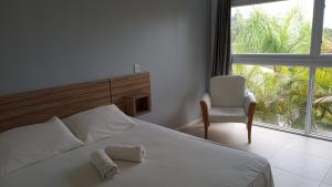 a bedroom with a bed and a chair and a window at Pousada Morro do Rosa in Praia do Rosa +200 photos