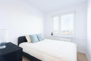 a white bedroom with a bed and a window at 19 Apart in Gdynia