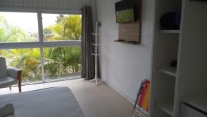 a living room with a large window and a couch at Pousada Morro do Rosa in Praia do Rosa
