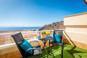 een balkon met een tafel en stoelen en de oceaan bij Eden Luxury Home in Puerto de Santiago