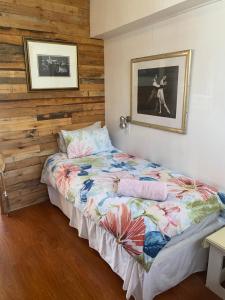 a bedroom with a bed with a wooden wall at Dancers' Cottages in Cape Town