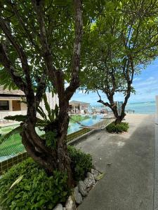 two trees next to a swimming pool next to the ocean at Punnpreeda Beach Resort - SHA Plus Certified in Bangrak Beach