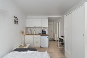 cocina pequeña con armarios blancos y nevera blanca en Pramonės Apartment #7 by PoloApartments, en Kaunas