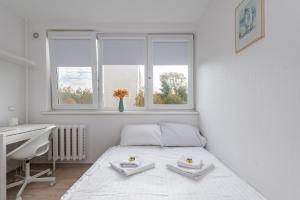 a white bedroom with a bed and a desk and windows at Pramonės Apartment #8 by PoloApartments in Kaunas