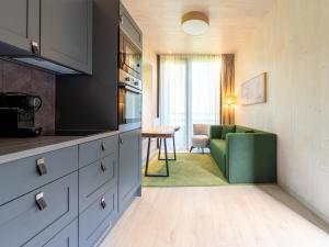 a kitchen with a green couch and a living room at Cosy Forest Hideaway for Two in Antoing