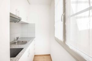 a white kitchen with a sink and a window at Saint Laurent 33-35 by Homenhancement in Lausanne