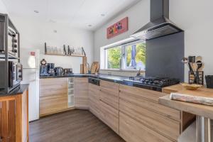 a large kitchen with wooden cabinets and a window at Pelikaanweg 21 in De Koog +24 photos