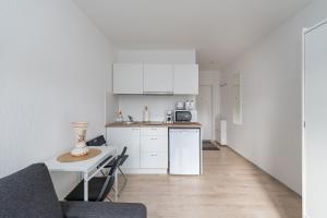 a kitchen with white cabinets and a table and a counter at Pramonės Apartment #9 by PoloApartments in Kaunas