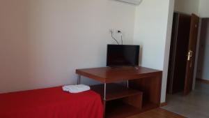 a room with a bed and a television on a table at Hotel Torrevado in Las Grutas