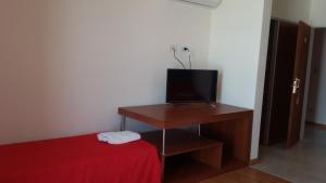 Habitación con cama y mesa con TV. en Hotel Torrevado en Las Grutas
