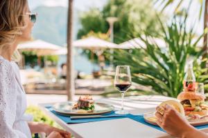 a woman sitting at a table with food and a glass of wine at Hotel la Palma au Lac in Locarno