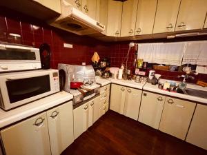 a kitchen with white cabinets and a microwave at Milk-ya Women-Only Guest House in Yomitan