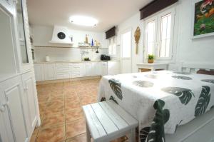 a white kitchen with a table and a bench in it at Livingtarifa Chalet La Caracola in Tarifa