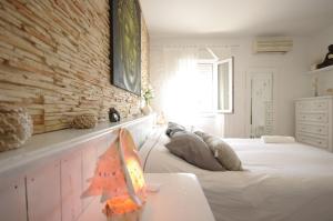 a bedroom with a white bed and a brick wall at Livingtarifa Chalet La Caracola in Tarifa