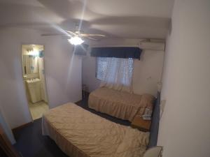 a small bedroom with two beds and a ceiling fan at Hotel Torrevado in Las Grutas