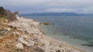 a rocky shoreline with the ocean and mountains at Apartments Vila Marica in Rabac