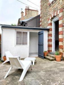 a patio with two white benches in front of a building at Charmant Studio au cœur de Dinard in Dinard