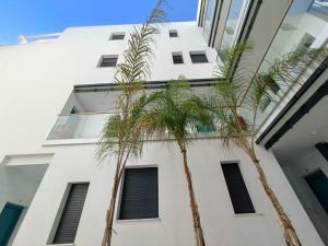 dwie palmy przed białym budynkiem w obiekcie Livingtarifa Apartamento La Palmera w mieście Tarifa