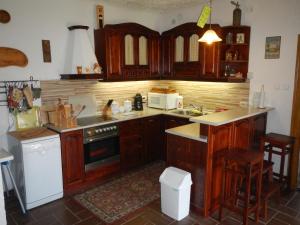 a kitchen with wooden cabinets and a stove top oven at Berki Porta Vendégház in Dinnyeberki