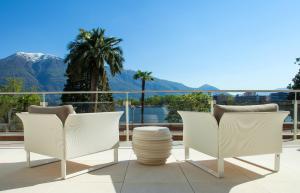 two chairs and a table on a balcony with mountains at Hotel la Palma au Lac in Locarno