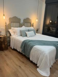 una camera da letto con un grande letto con coperte e cuscini bianchi di Apartamentos Rurales El Solsuco ( La Galería) a Villaviciosa