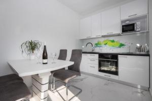 a white kitchen with a white table and chairs at Apartments Ivan in Postira