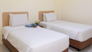 two beds in a room with white sheets at Hotel Wisata Banda Aceh in Banda Aceh