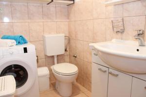 a bathroom with a toilet and a sink and a washing machine at Apartments Lucia in Supetar