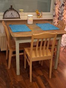 a wooden table with two chairs and a table with blue mats at Tunnelmallinen retroyksiö in Rovaniemi