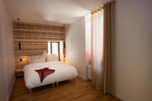 a bedroom with a bed with white sheets and a window at Les chambres de l'Alouette in Ponas