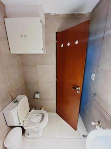 Un baño con inodoro y puerta de madera. en Luminoso y Moderno Departamento en el Centro de Bariloche, en San Carlos de Bariloche