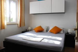 a bedroom with a bed with orange pillows and a white cabinet at Apartments Lucia in Supetar