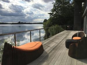 レッチレードにあるLuxury Lakeside House at Lakes by Yooの水辺の景色を望むウッドデッキ(ベンチ付)