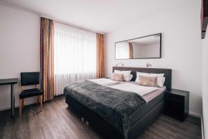 Un dormitorio con una cama con un espejo y una silla. en Hotel International am Theater, en Münster