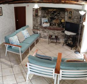 a living room with a couch and chairs and a television at Casa da Guida in Paul do Mar
